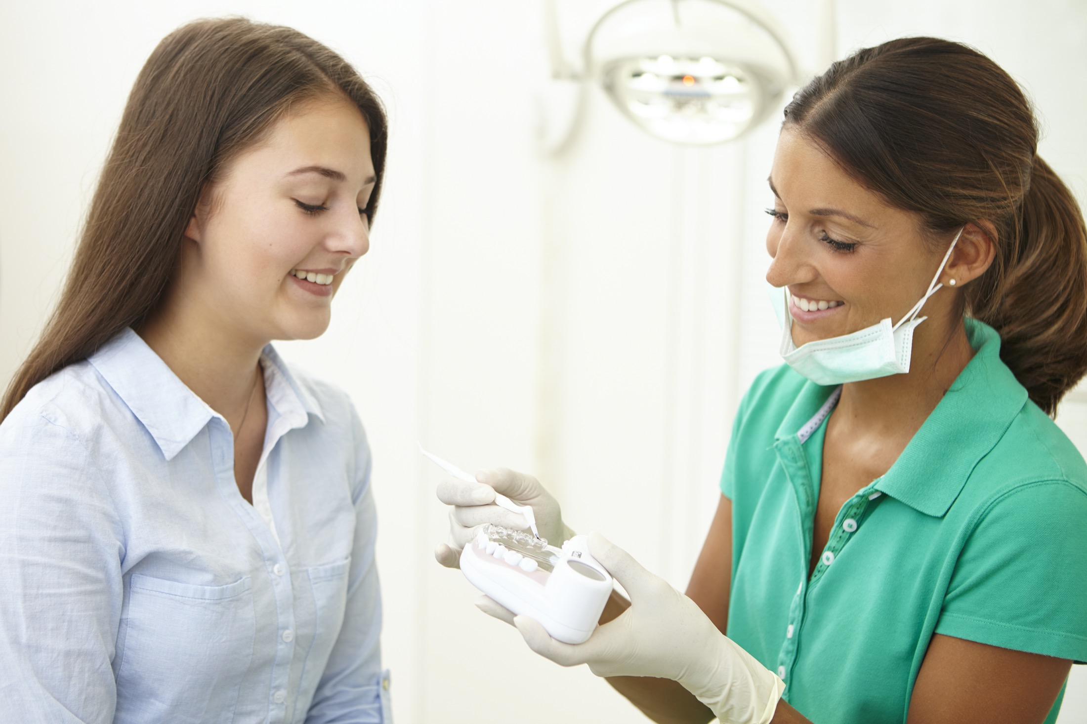 Zahnärztin zeigt einer jungen Patienten wie eine Behandlung aussehen wird